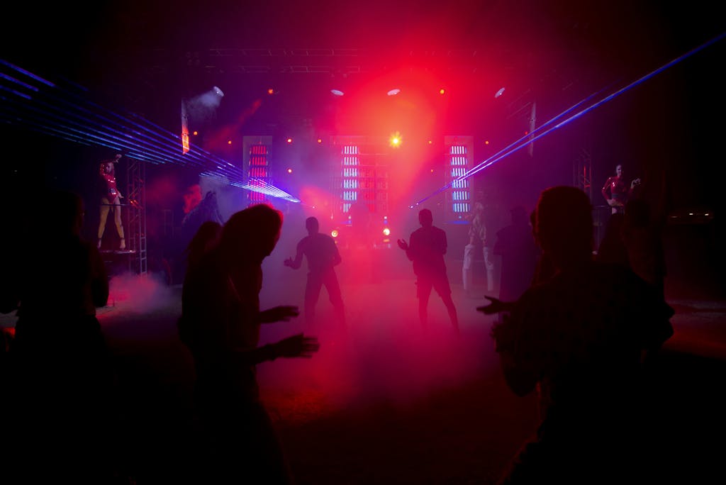 Silhouetted dancers in a nightclub with striking laser lights and a vibrant atmosphere.